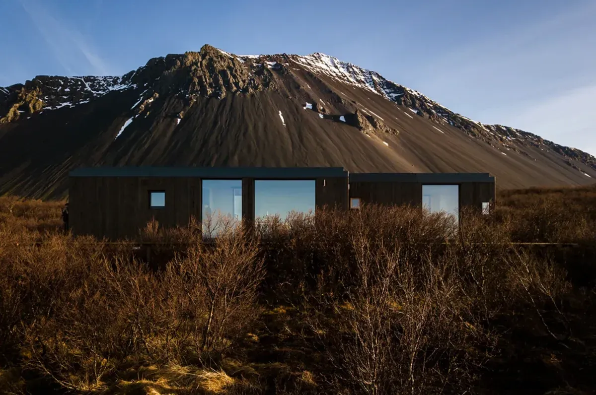 Black cabin beneath striped mountain