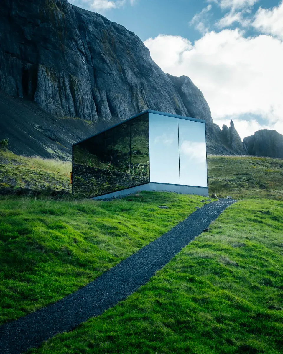 Modern glass structure beneath dramatic Icelandic basalt cliffs